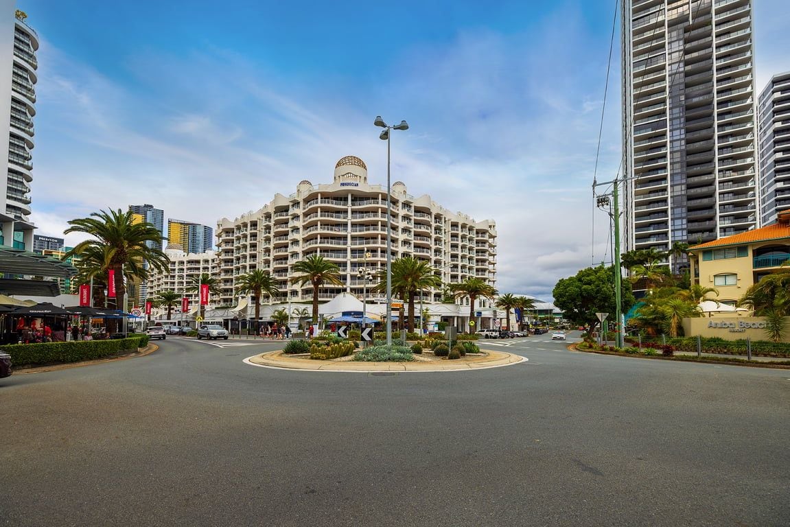 A multi-story hotel with a central courtyard, surrounded by palm trees and other greenery.