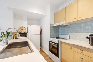 A compact kitchen with white cabinetry, a microwave, a stove, and a sink.