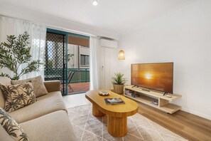Ein modernes Wohnzimmer mit Sofa, Couchtisch, Fernseher und einem Balkon mit Blick.