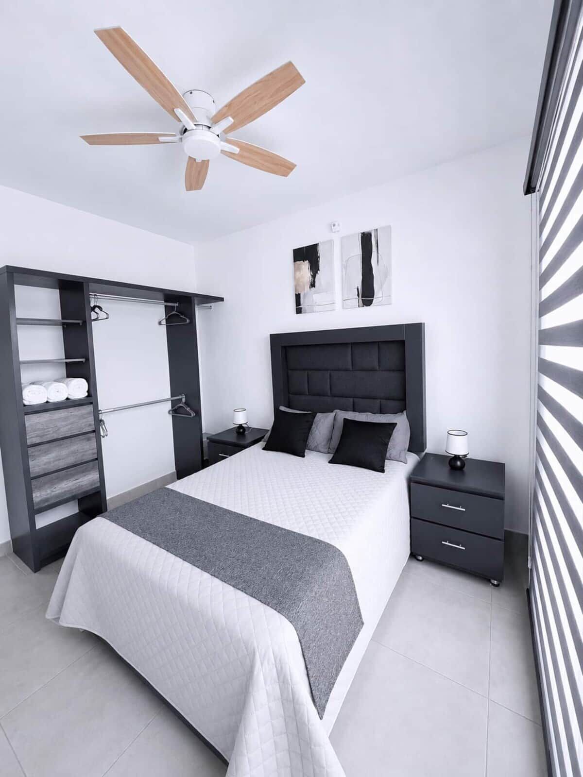 Un dormitorio moderno con cama, mesitas de noche, armario y ventilador de techo.