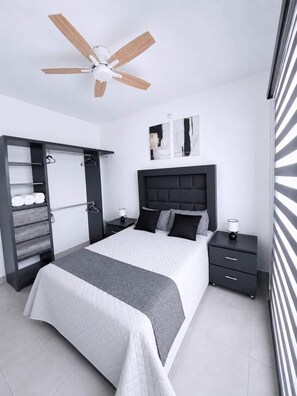 Un dormitorio moderno con cama, mesitas de noche, armario y ventilador de techo.