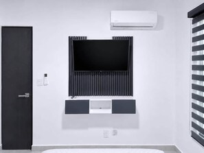 A modern room with a mounted TV, air conditioning unit, and a door. - Nice Apt+Pool+Beach Club+Parking+Gym+AC@Acapulco Diamante (Acapulco)