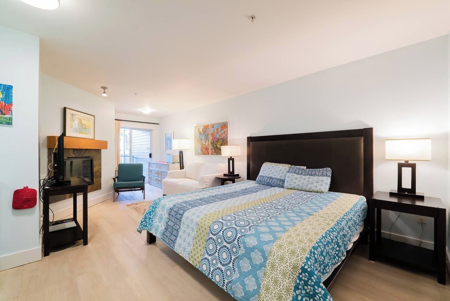 Habitación de hotel con una cama grande, televisión, chimenea, escritorio y una silla.