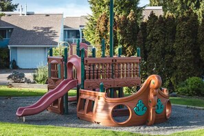 Un parque infantil con tobogán, estructuras de escalada y una zona de juegos con temática náutica.