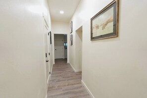 A hallway with a wooden floor, white walls, and a framed picture on the right. - North Beacon Hill Seattle Retreat, Sauna, Jacuzzi Tub, King Bed, Central Locale! (Seattle)