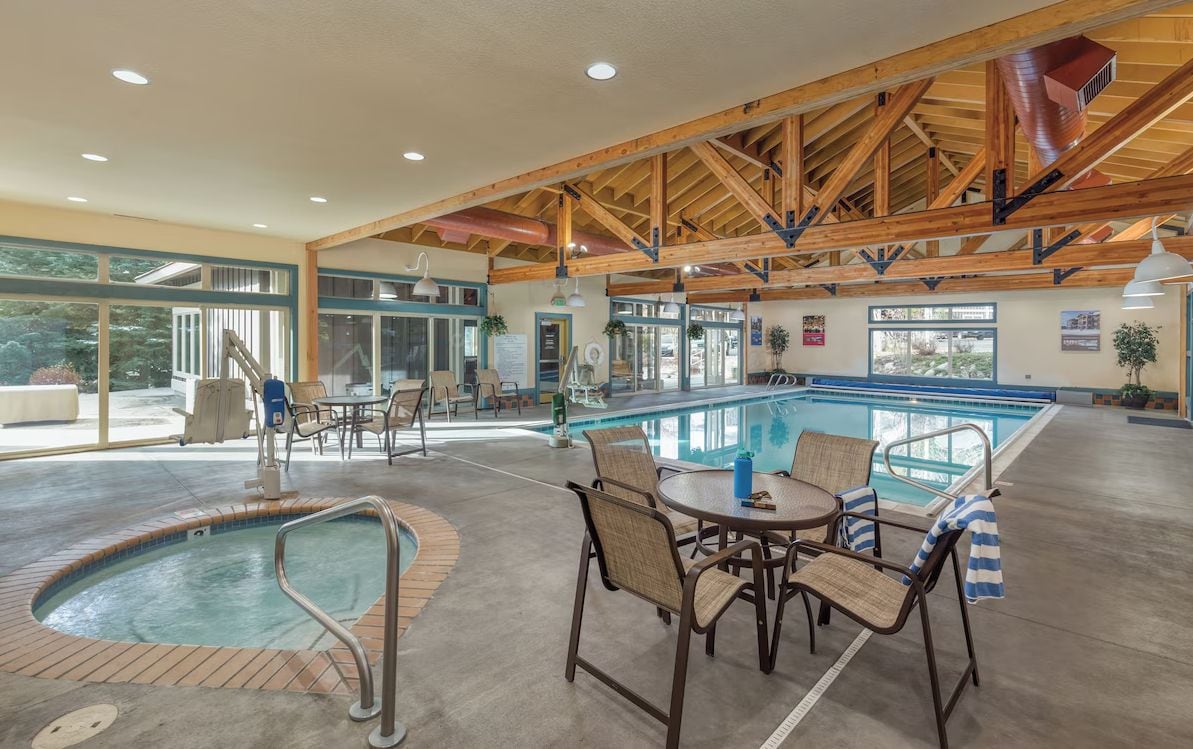 A pool area with a hot tub, lounge chairs, and a covered seating area.
