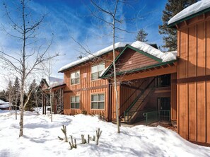 A wooden cabin with a snow-covered roof, a staircase leading to a door, and a clear blue sky. - Spacious, Comfortable & Cozy 2-bedroom condo in charming McCall (McCall)