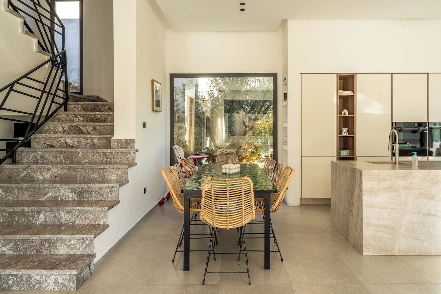 A modern interior with a staircase, dining area, and kitchen.
