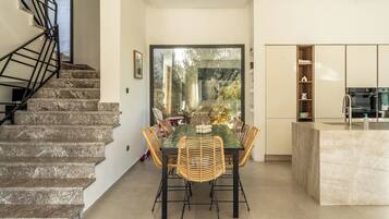A modern interior with a staircase, dining area, and kitchen.