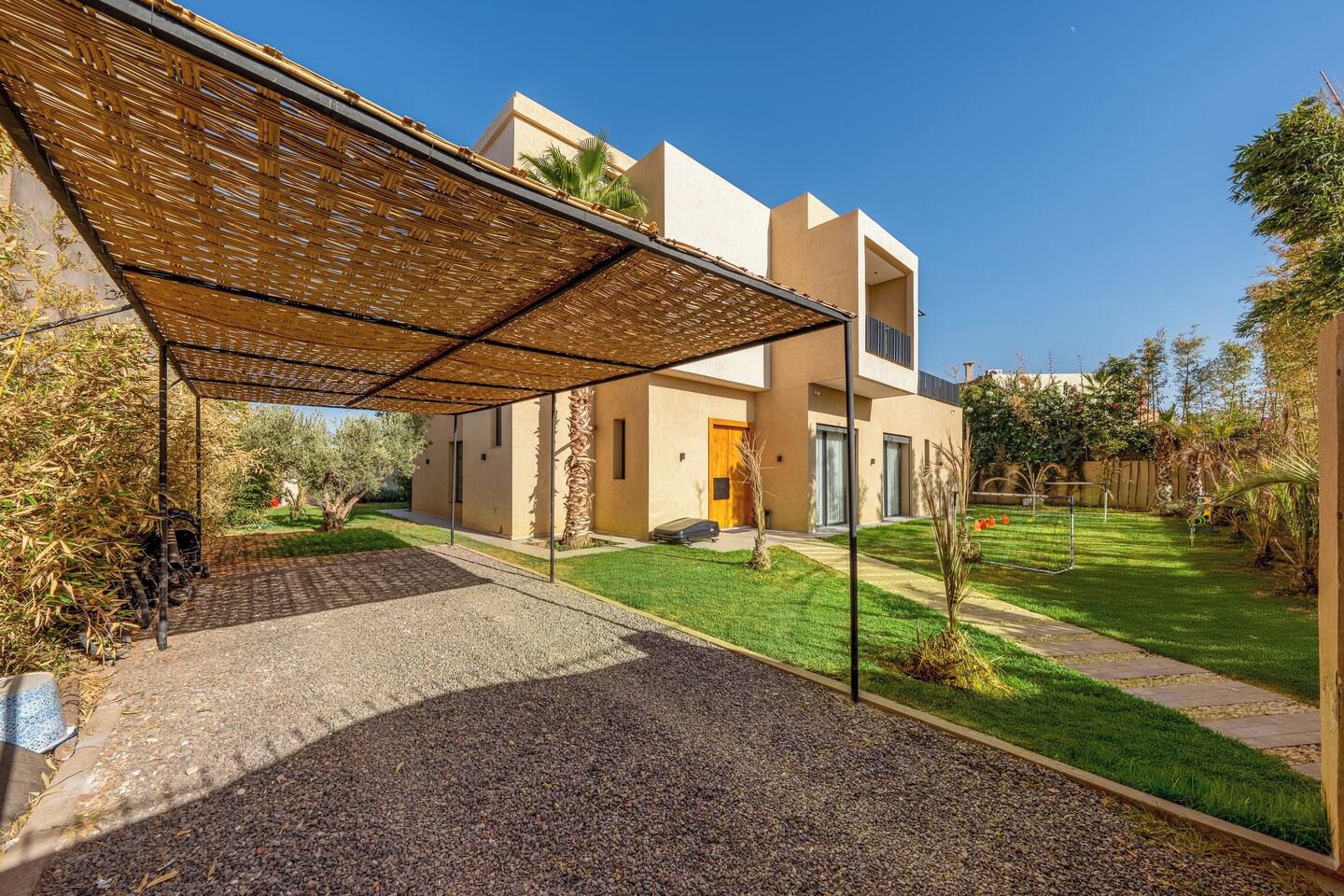 A modern house with a covered patio, a well-maintained lawn, and a gravel driveway.