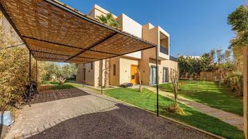 A modern house with a covered patio, a well-maintained lawn, and a gravel driveway.