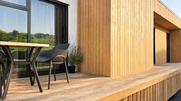 Ein moderner Außenbereich zum Sitzen mit einer Holzterrasse, einem Tisch und zwei Stühlen.
