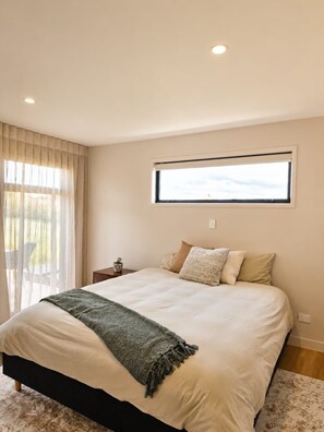 Een slaapkamer met een bed, een raam, een nachtkastje en uitzicht op de omgeving.