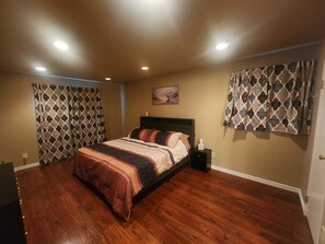 A bedroom with a bed, nightstand, and patterned curtains. - Versatile Fully Furnished 2 Bed/2 Bath Condo near Anschutz, Buckley SFB, and DIA (Aurora)