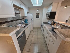 A kitchen with white cabinets, a microwave, a coffee maker, and a clock on the wall. - Versatile Fully Furnished 2 Bed/2 Bath Condo near Anschutz, Buckley SFB, and DIA (Aurora)