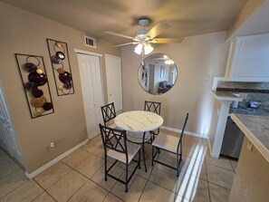 A dining area with a round table, chairs, a ceiling fan, and a mirror on the wall. - Versatile Fully Furnished 2 Bed/2 Bath Condo near Anschutz, Buckley SFB, and DIA (Aurora)