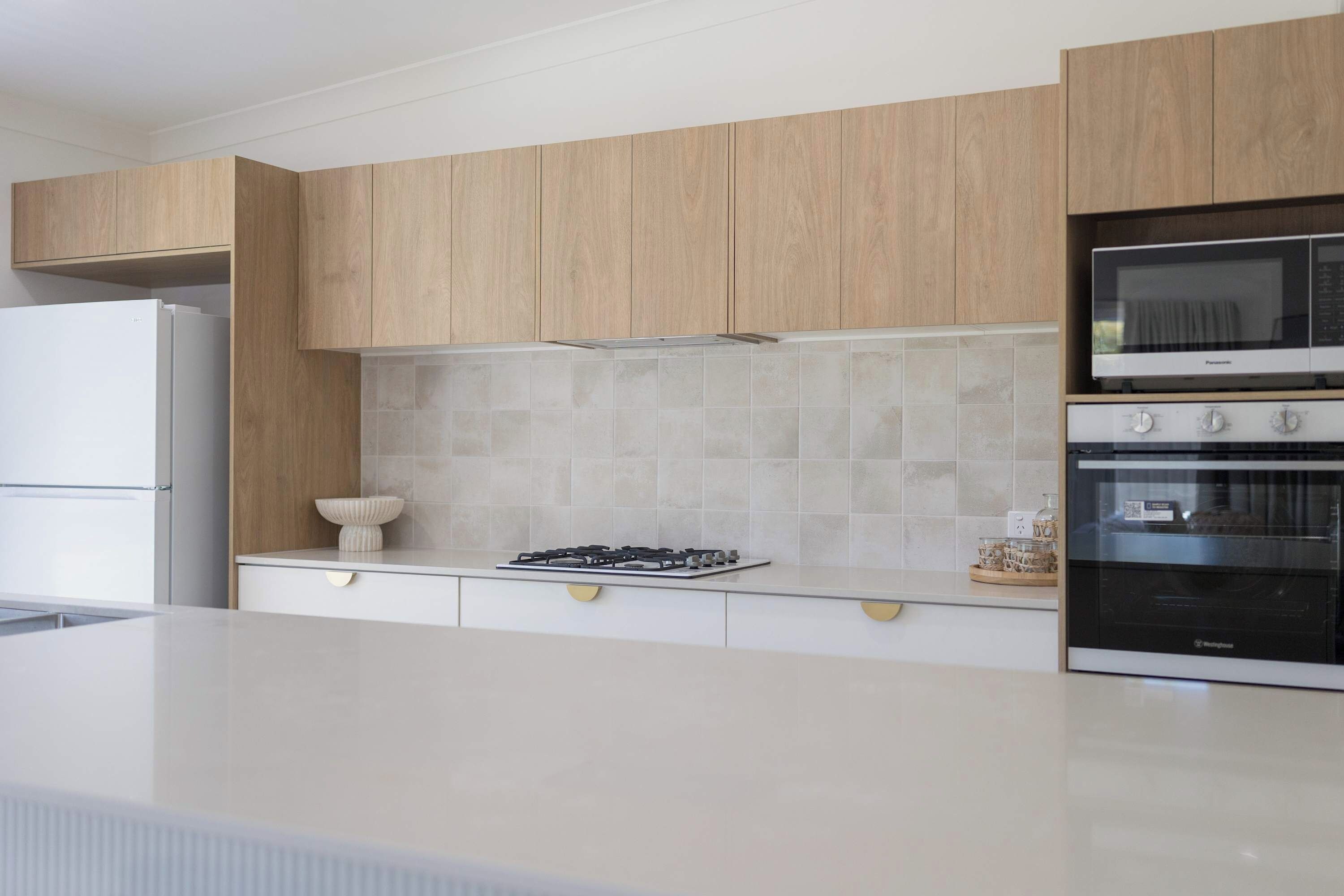 Eine moderne Küche mit Holdekor, einem weißen Kühlschrank, einem Gasherd und einem eingebauten Backofen.