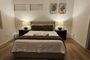 A neatly made bed with a brown headboard, two bedside tables with lamps, and two wall-mounted artworks. - Modern Spacious 1-BR Automated Haven: Work-Ready - Private Room in Townhome (Seattle)