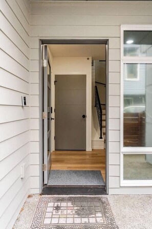 A doorway leading to a room with a wooden floor and a door with a black handle. - Modern Spacious 1-BR Automated Haven: Work-Ready - Private Room in Townhome (Seattle)