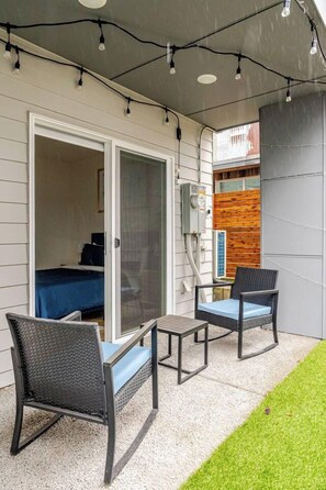 A patio with two wicker chairs, a small table, and a sliding glass door leading to a bedroom. - Modern 1-BR Automated Haven: Private Patio - Private Room in Townhome (Seattle)