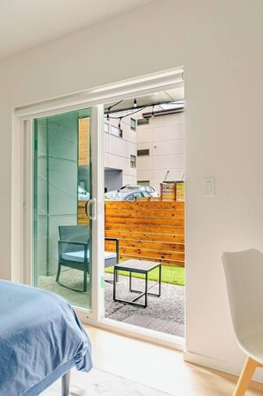 A room with a sliding glass door leading to an outdoor area with a wooden fence and a table. - Modern 1-BR Automated Haven: Private Patio - Private Room in Townhome (Seattle)
