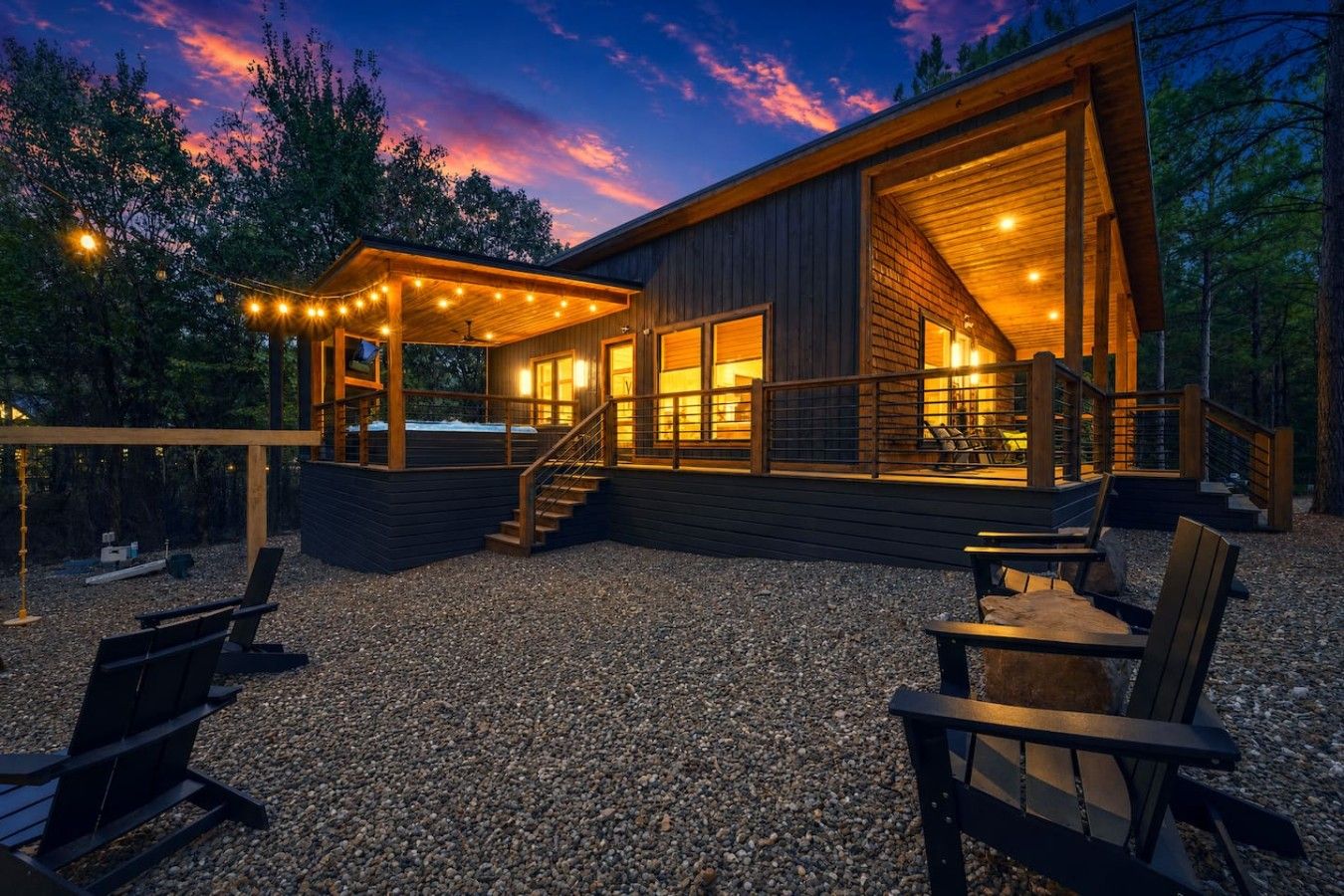 A wooden cabin with a covered porch, outdoor seating, and a staircase leading to the entrance.