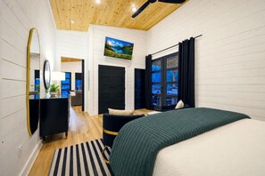 Een moderne slaapkamer met een bed, een grote spiegel, een televisie en uitzicht op het landschap.