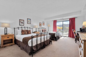 A hotel room with a large bed, two bedside tables, a desk, and a view of the outdoors. - Shadow Ridge 4123: Corner Unit, Walk to Ski -2Bedroom, 3 bath (Park City)