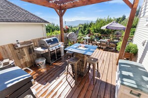 Eine Außenpatio mit Grill, Barhocker und einem Tisch mit Feuerstelle.