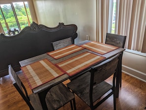 A dining table with four placemats, dark wooden chairs, and a view of greenery through a window. - Lakefront 3-bedroom house with AC in cozy Eatonton (Eatonton)