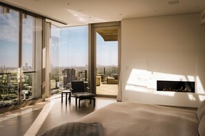 A modern living room with a large window, a fireplace, and a city view. - Gatsby Mansion (West Hollywood)