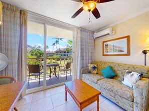 A hotel room with a balcony, a ceiling fan, a sofa with patterned cushions, and a framed picture on the wall. - Islander on the Beach | Oceanview, A/C, Pool (Kapaʻa)