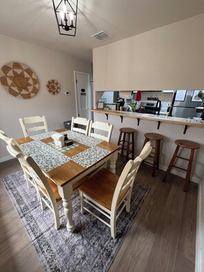 A dining area with a wooden table, white chairs, and a patterned rug. - 3-bedroom house close to Lackland AFB, Seaworld and Downtown San Antonio (San Antonio)