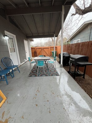 A covered patio with a table and chairs, a barbecue grill, and a wooden fence in the background. - 3-bedroom house close to Lackland AFB, Seaworld and Downtown San Antonio (San Antonio)