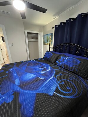 A bedroom with a bed featuring a blue and black patterned bedspread, a dark headboard, and a ceiling fan. - 3-bedroom house close to Lackland AFB, Seaworld and Downtown San Antonio (San Antonio)