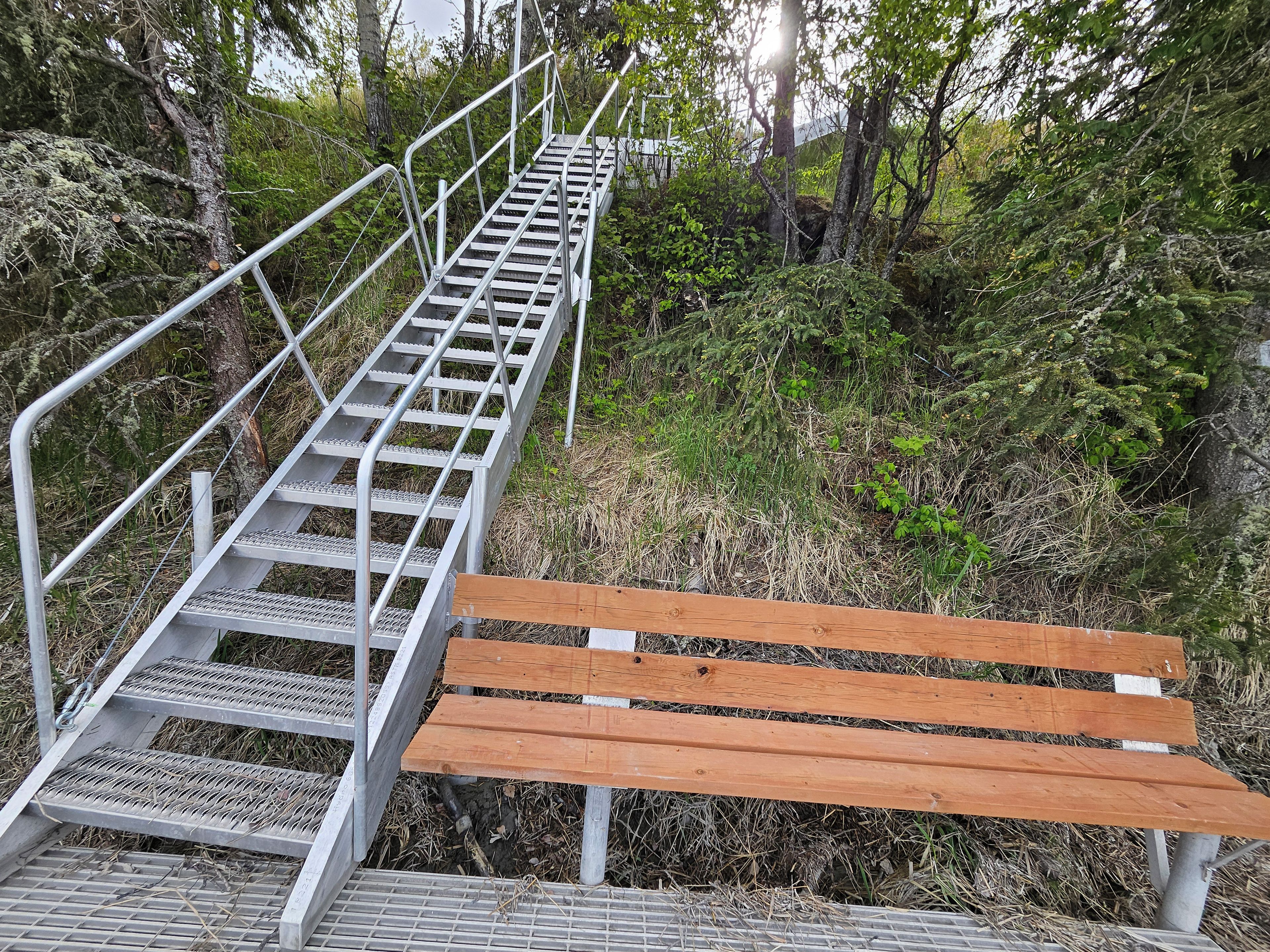 Una escalera de metal con un banco de madera al pie.