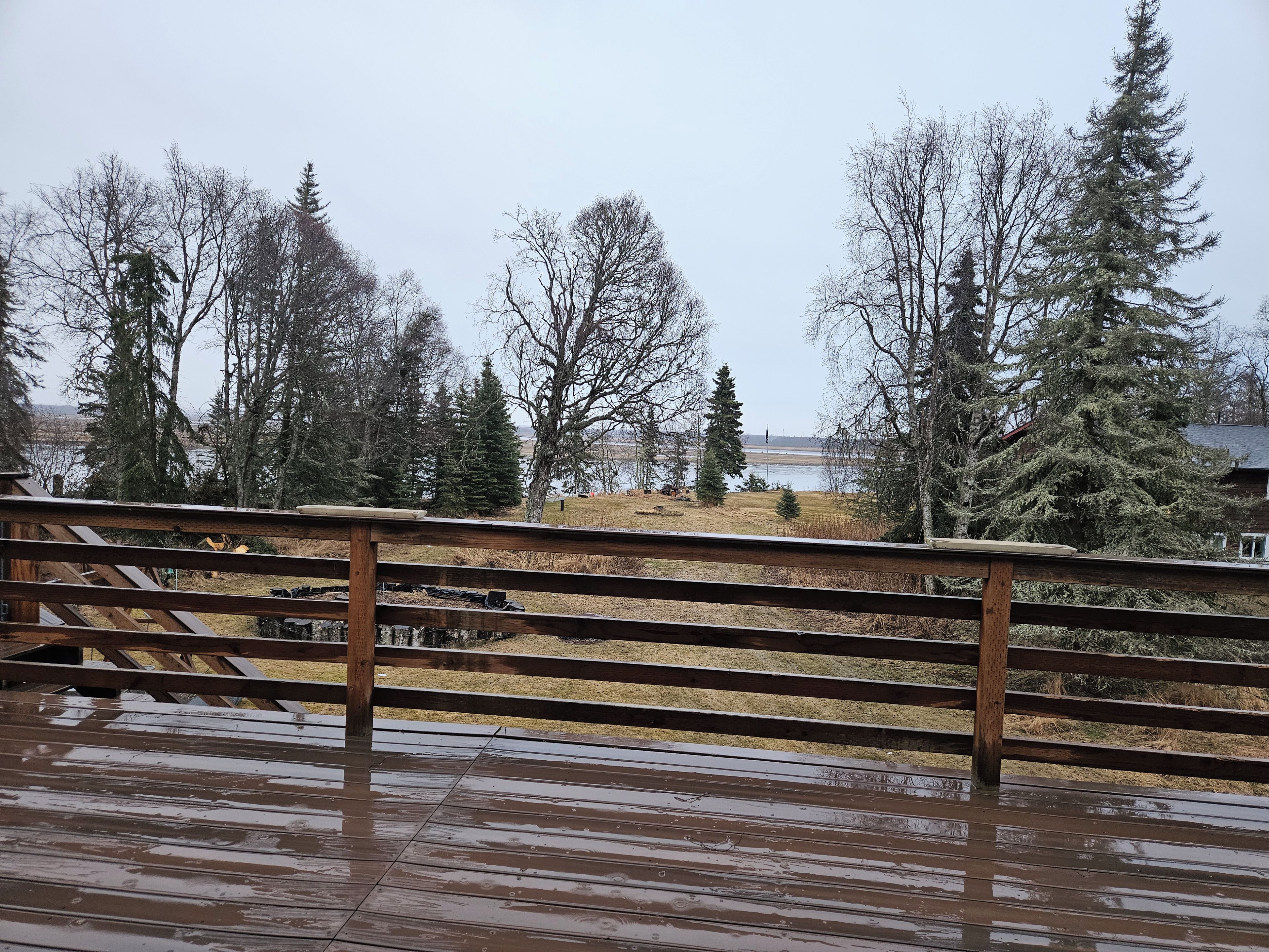 Una terraza de madera con vista a un lago y árboles.