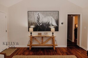 A hallway with a wooden console table, two wall-mounted lamps, and a framed picture of a horse. - Synergy at IGF - Beautiful 3-bedroom house in charming Hawkinsville (Hawkinsville)