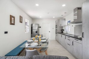 Cozinha moderna com área de jantar, equipada com geladeira, forno e coifa de aço inoxidável.