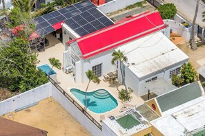 A residential property with a swimming pool, solar panels, and a red-roofed building. - NEW 3BD Family Home Little Gem by Signature Stays (Oranjestad)