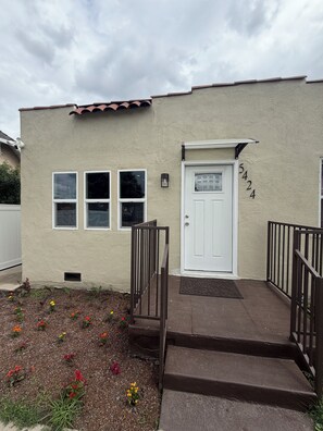 A single-story building with a white door, numbered 5424, and a small porch with steps leading to the entrance. -  2-bedroom apartment with gated parking (Los Angeles)