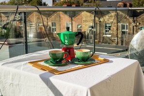 A table with a coffee maker, two cups, and a tray on a balcony with a view of buildings. - Bright 1BR Flat with Balcony in London Fields (London)