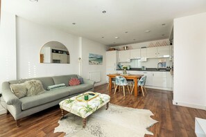 A modern living room with a sofa, a coffee table, and a dining area with chairs. - Bright 1BR Flat with Balcony in London Fields (London)