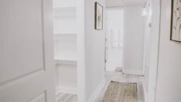 A hallway with white walls, a wooden floor, and a patterned rug.
