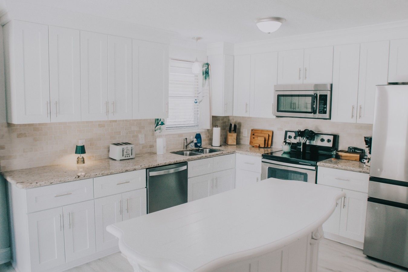 A modern kitchen with white cabinetry, a microwave, a stove, and a dishwasher.