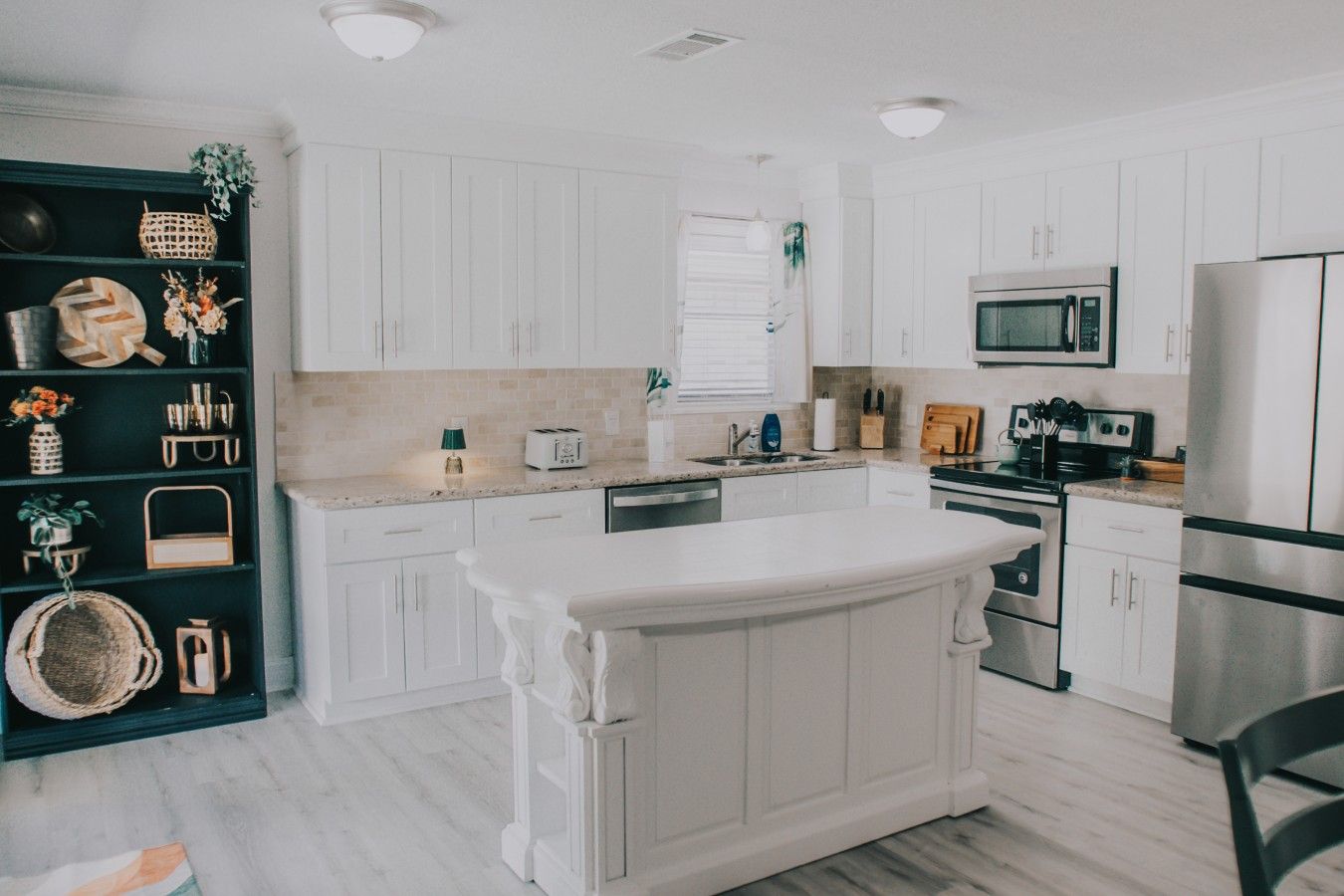Una cocina moderna con armarios blancos, una isla central y un microondas integrado.