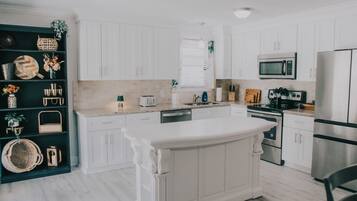 Una cocina moderna con armarios blancos, una isla central y un microondas integrado.