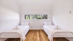 A room with two single beds, a window with a view of trees, and wooden flooring. - The White Honey Cottage - Newly Renovated 4BDR on White Street (West Tamworth)