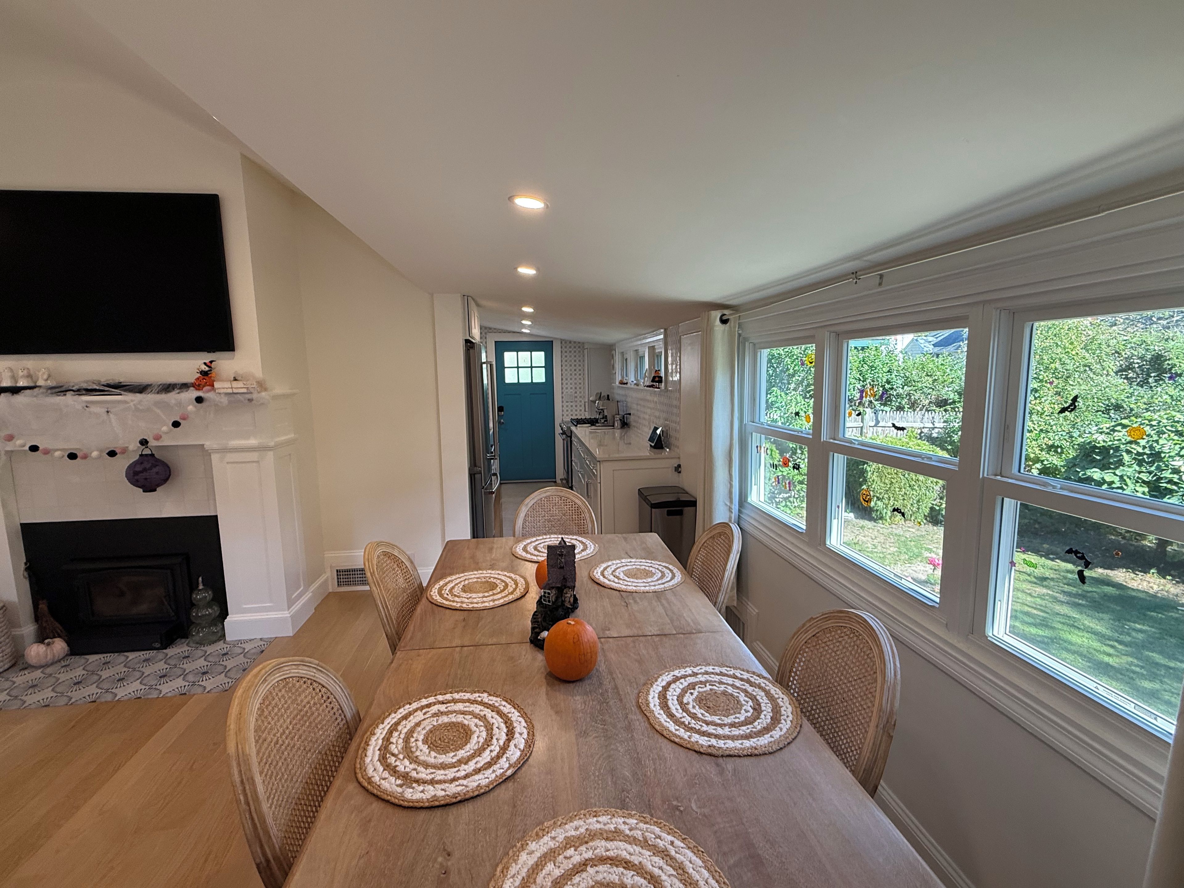 A dining area with a long table, chairs, and a fireplace.