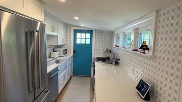 A modern kitchen with stainless steel appliances, a blue door, and a digital clock.